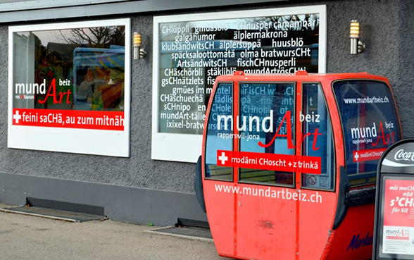 Painel publicitário de um restaurante escrito em suíço alemão.