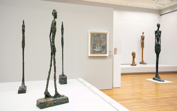 A display of bronze sculptures with elongated human forms such as 'l'Homme qui Marche'.