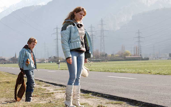Two young people standing next to a country road