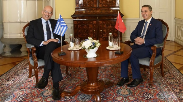 Sentado a una mesa de reunión, el consejero federal Cassis se entrevista con el ministro de exteriores griego Nikos Dendias.