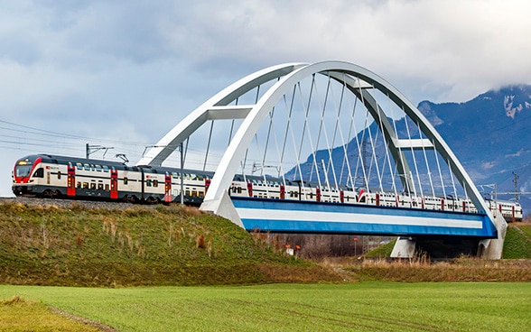 Moderno trem de passageiros de dois andares na ponte sobre o Rhône, próximo a Massongex.