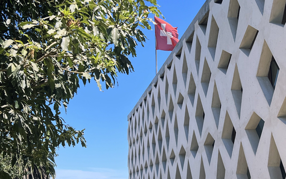 Bâtiment vu de l'extérieur avec le drapeau suisse de la Chancellerie de l'Ambassade.