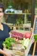 Biljana, Mitbegründerin der Bio-Genossenschaft «Unsere gute Erde», hält eine Kiste mit Biofrüchten und gemüse.