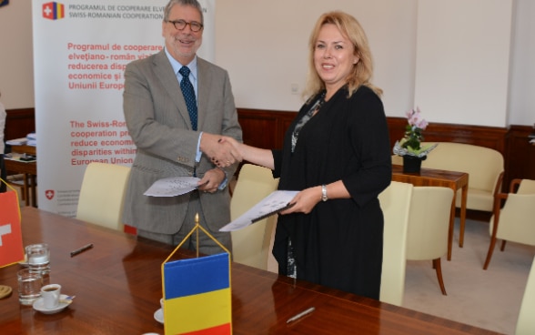 Ambasadorul Urs Herren și Ministrul Aura Dragu fac schimb de documente semnate