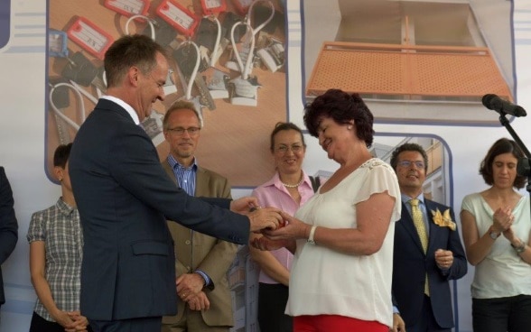 Swiss Ambassador handing over apartment keys to one of the refugee families