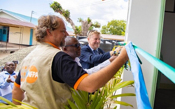 Mr. Mark Bryan Schreiner, Prof. Jamal Katundu and Mr. Holger Tausch cut the ribbon to mark the official handover.  