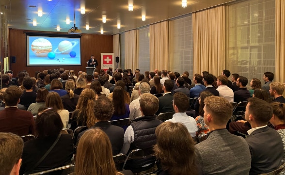 a room of people listening to a speaker