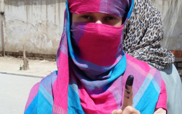 A female voter shows her left index colored with ink after she cast her ballot