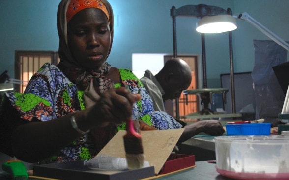 Une femme malienne confectionne une boîte de conservation.