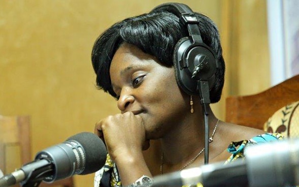 An African woman talks into the microphone in a radio studio. 