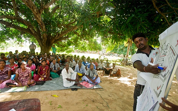 Con l’aiuto di uno schema, un esperto della DSC consulta una cinquantina di abitanti di un villaggio dello Sri-Lanka per organizzare le operazioni di ricostruzione.