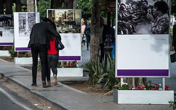 A couple walking along the avenue in which the photos in the Making Peace exhibition are on display.