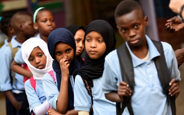 Children and young people from different countries walking in a line.