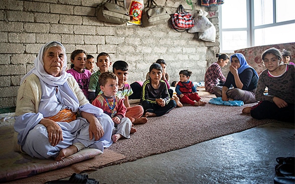 Des femmes et des enfants sont assis sur le sol d’une petite maison dans un village kurde au nord de l’Iraq,