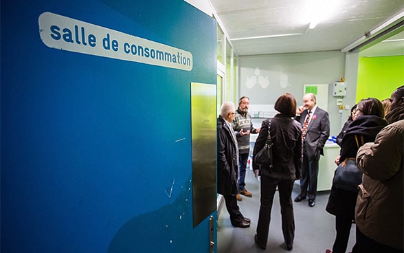 A group of visitors listens as a senior staff member explains something in the drug consumption room in Quai 9.