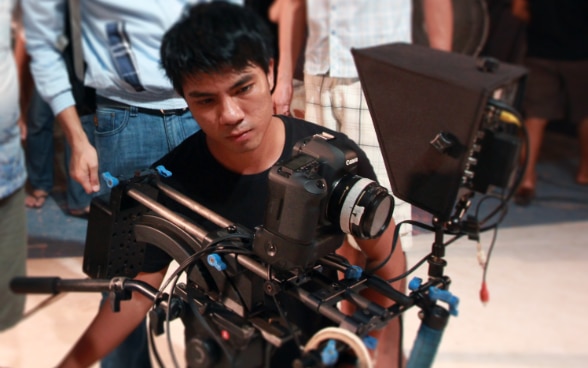 Un jeune réalisateur birman derrière une caméra procède au tournage d’un film.