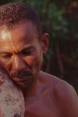 A Brazilian fisherman tightly embracing to his chest the fish he has just caught .
