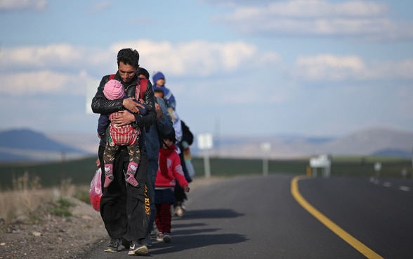 A refugee family walks along a road