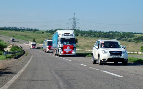Camioni con bandiere svizzere sul cofano ruggito attraverso la steppa ucraina. 