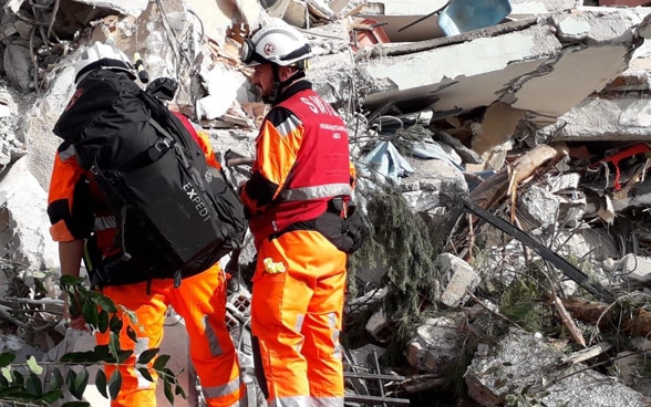 Deux hommes du Corps suisse d’aide humanitäre devant un bâtiment effondré. 