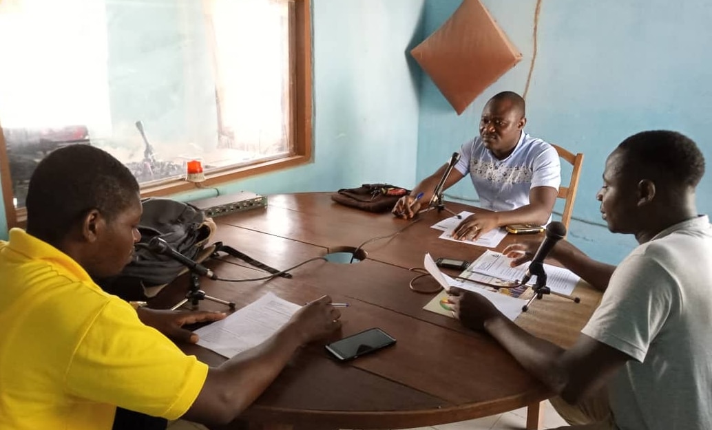 Three men with microphones around a table taking part in a radio discussion. 