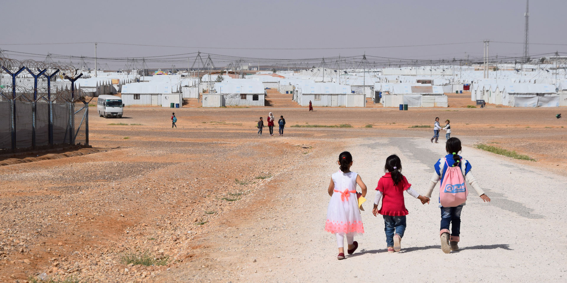 Drei Mädchen laufen über einen Kiesweg im Flüchtlingslager Azraq in der jordanischen Wüste.