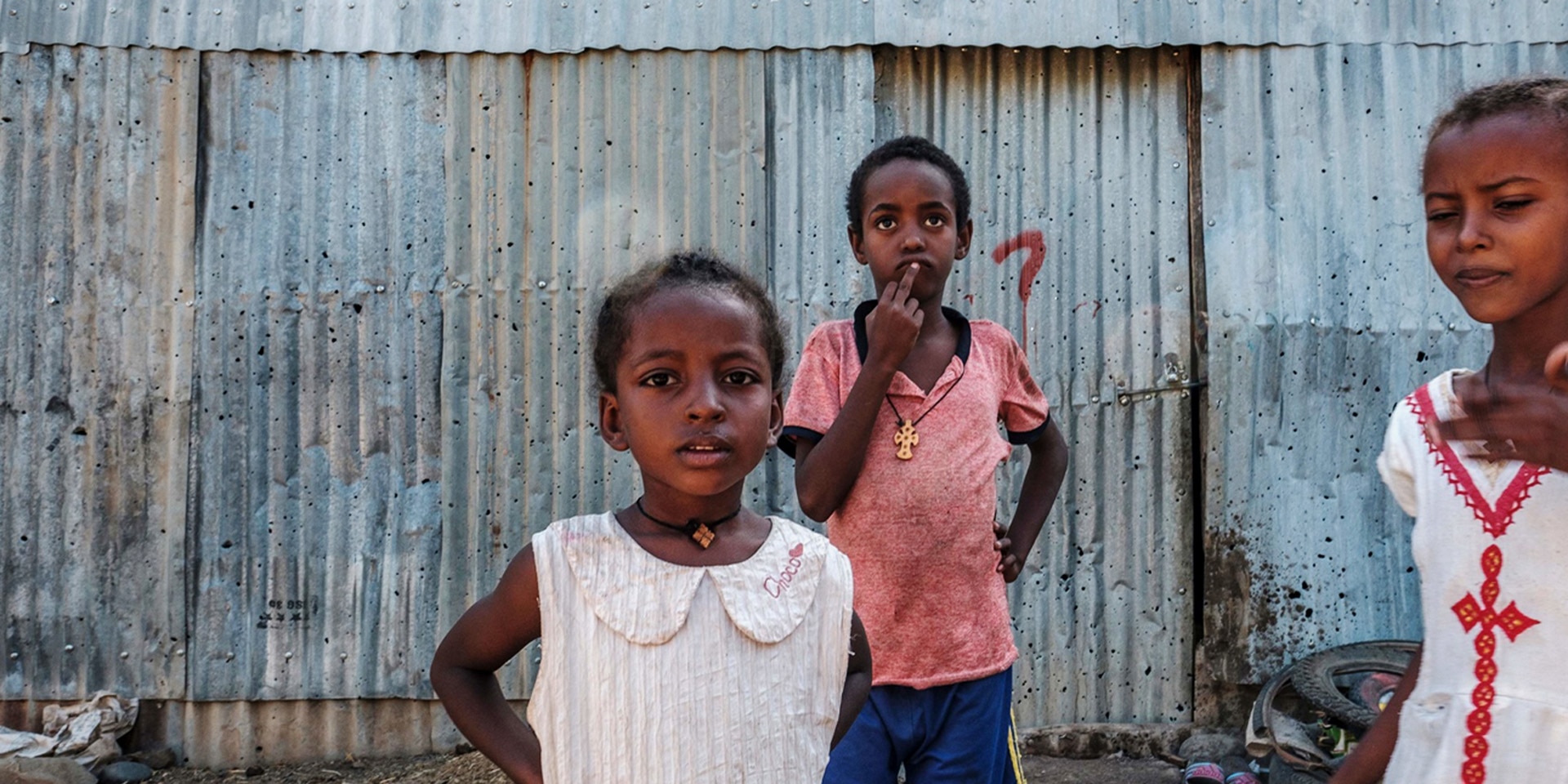 Young girls stand in front of a sheet-metal house in Humera, Ethiopia