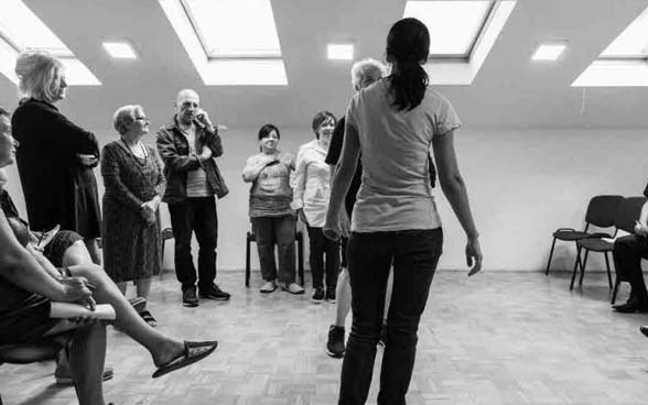 A group of carers trying out drama therapy in a room.