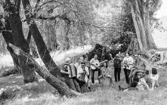 Dans une clairière, plusieurs personnes font de la musique ensemble.