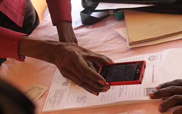 Una mujer utiliza su teléfono móvil para escanear un código QR impreso en una hoja de papel.