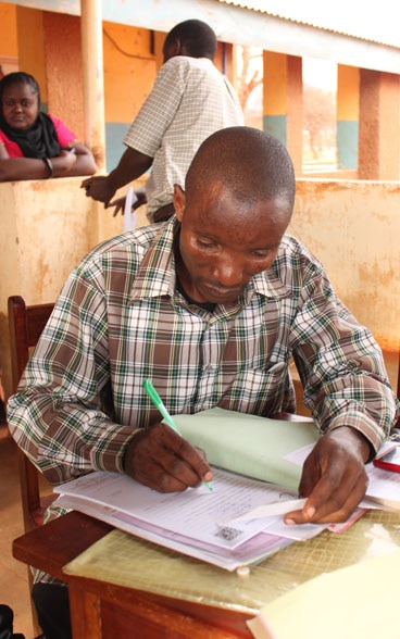 A man sitting at a desk is filling in a form. 