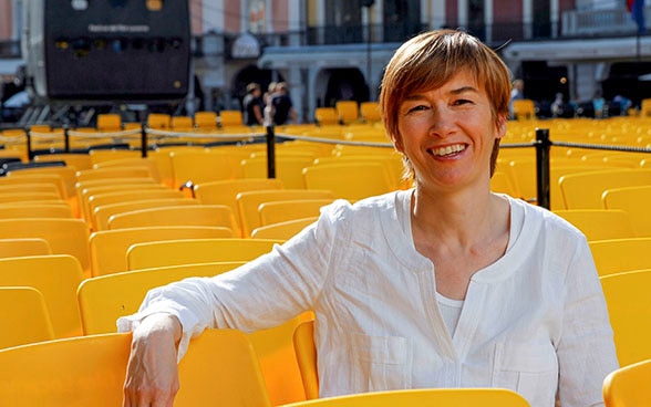 Head of Open Doors Sophie Bourdon sitting on one of the yellow seats at the Locarno Film Festival in Locarno's Piazza Grande.