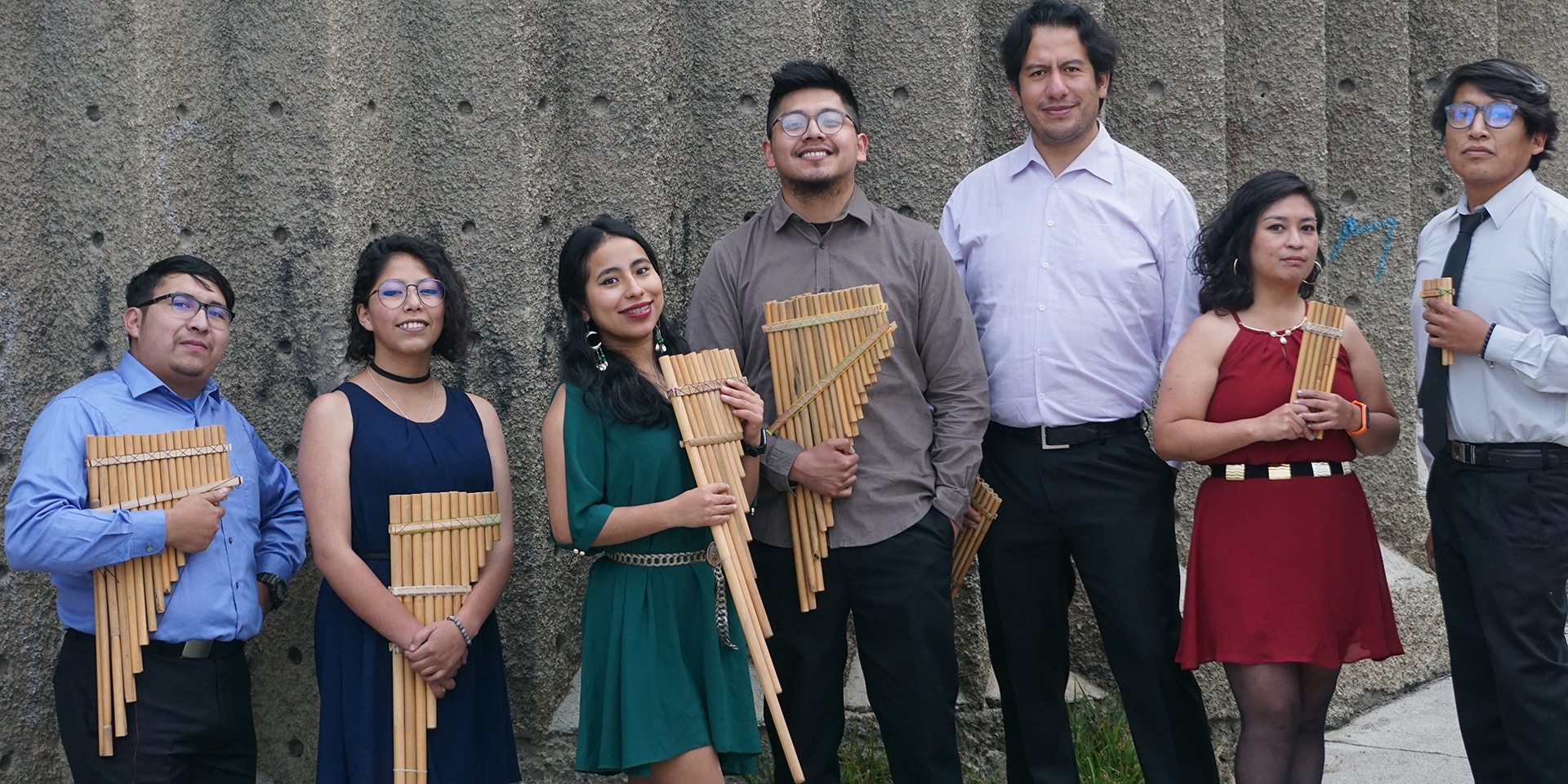 Les sept musiciens de l'Ensemble OEIN sont debout et tiennent dans leurs mains des flûtes de pan. 