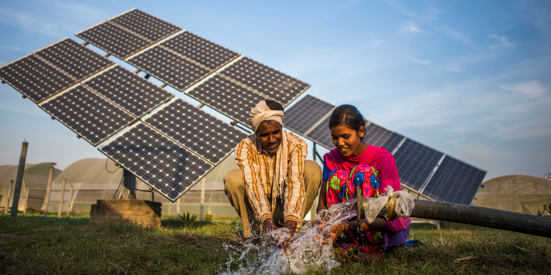 Un uomo e una donna nel Sud del mondo con un tubo dell’acqua e sullo sfondo pannelli solari.
