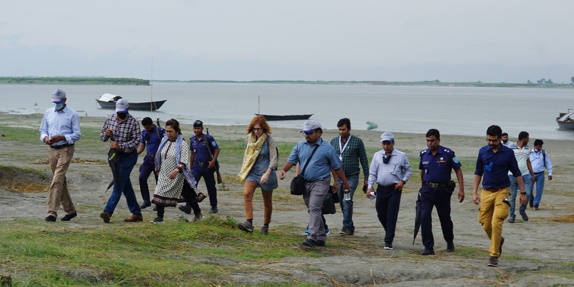 Mujeres y hombres caminan por una isla fluvial.