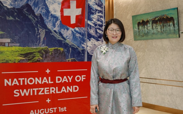 Portrait of Zolzaya Lkhagvasuren in front of a poster celebrating 1 August.