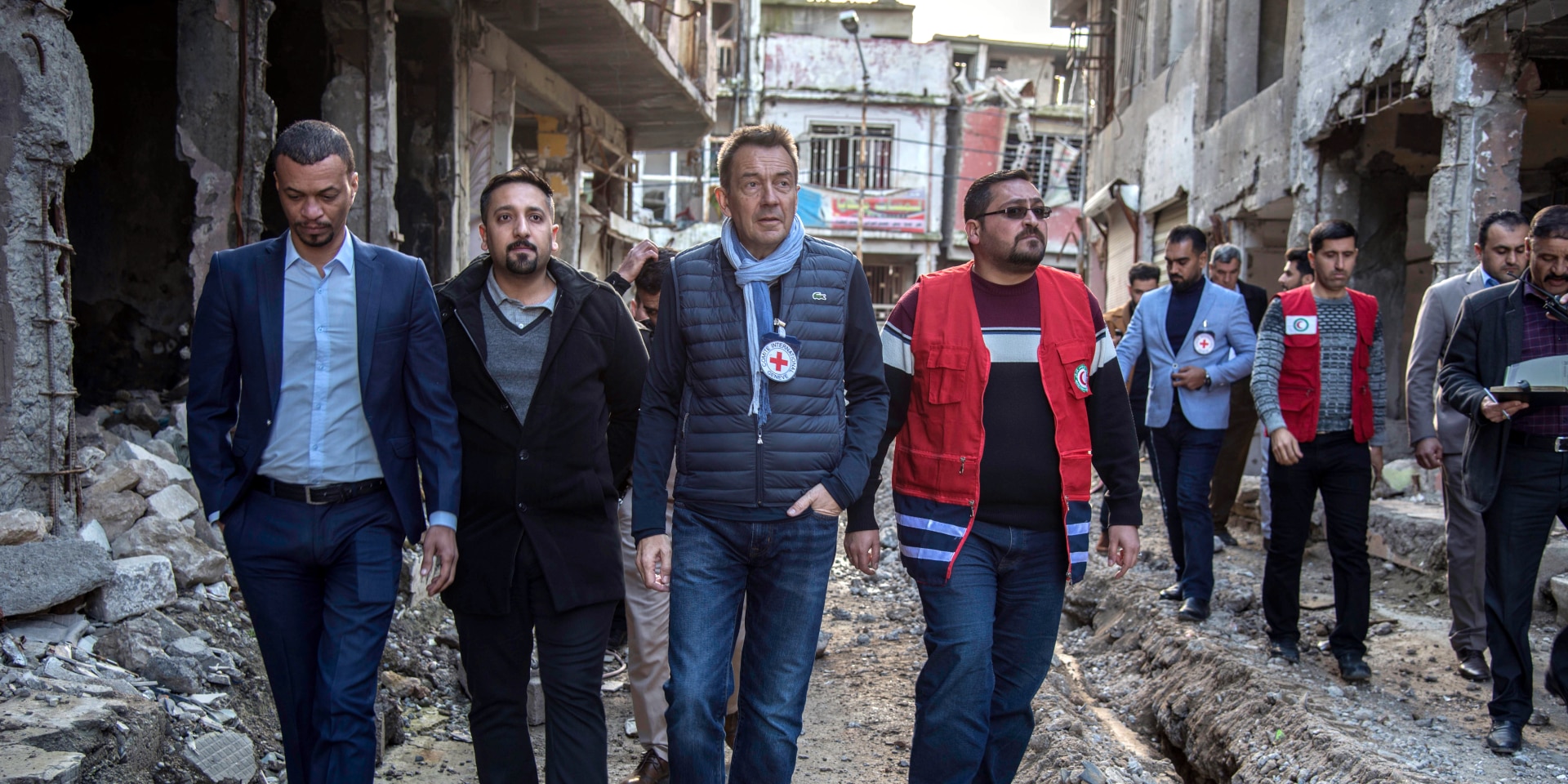 Peter Maurer, accompanied by ICRC and Red Crescent staff, makes his way through the ruins of a Mosul neighbourhood.