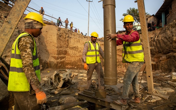 Auf einer Brückenbaustelle werden drei Arbeiter bei ihrer Arbeit fotografiert.