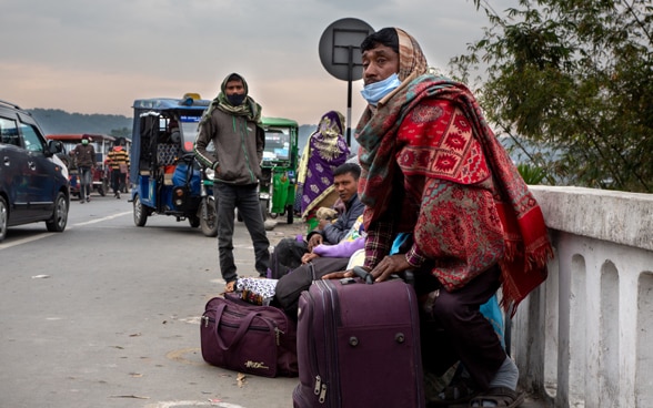  Nepalesen stehen mit ihrem Gepäck am Straßenrand und bereiten sich auf die Migration nach Indien vor.