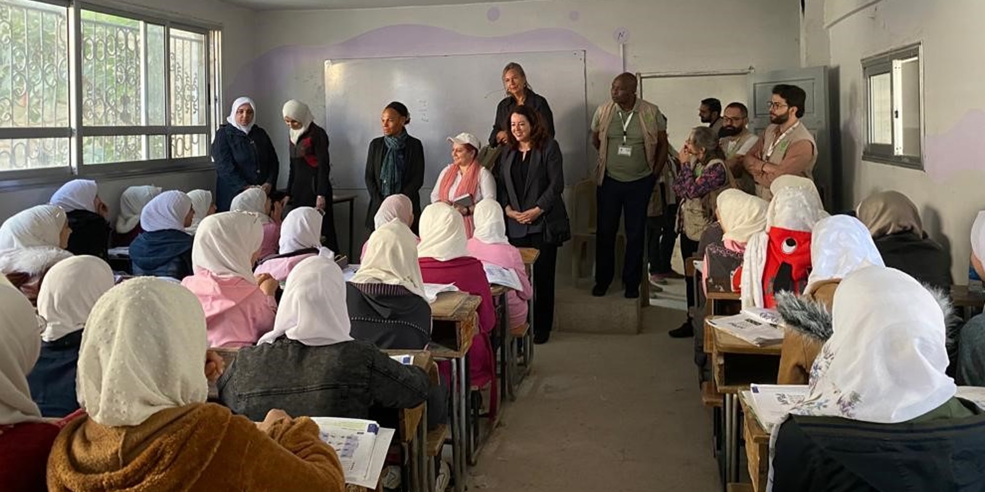 Mädchenschule in Syrien: Unter anderem sieht man DEZA-Direktorin Patricia Danzi und Botschafterin Maya Tissafi vor einer Wandtafel stehen, während sie sich mit Schülerinnen unterhalten.