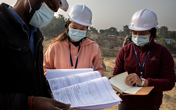 Two young women engineers at a construction site checking a plan.