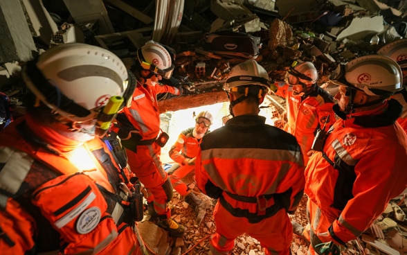  Sei membri della Catena di salvataggio si trovano tra le macerie di un edificio e parlano tra loro.