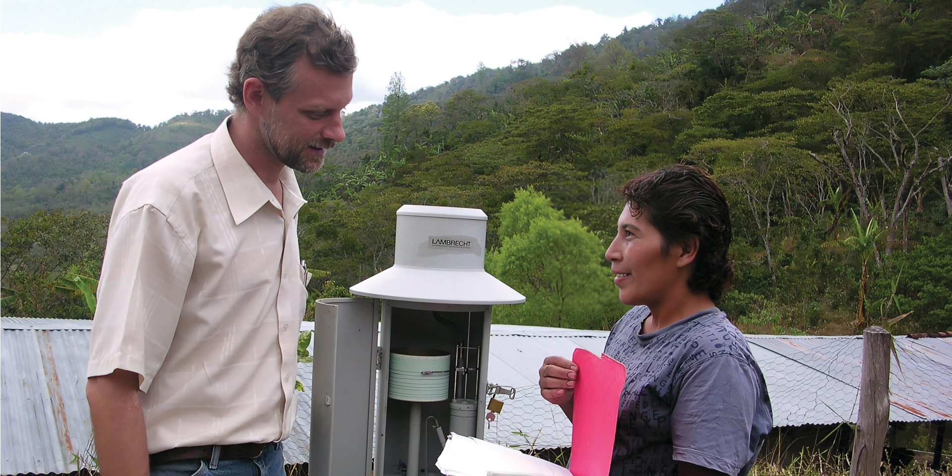 Un uomo e una donna parlano davanti a una stazione di monitoraggio climatico. 