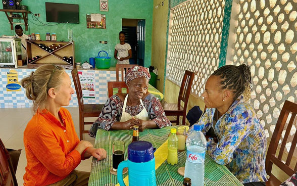 Three women sitting talking at a restaurant table: Patricia Danzi, a colleague from the Swiss cooperation office in Benin, and the Beninese restaurant owner.
