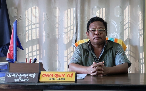 Un nepalí se sienta detrás de su mesa en la oficina.