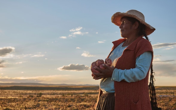 Une paysanne bolivienne tient des pommes de terre dans ses mains.