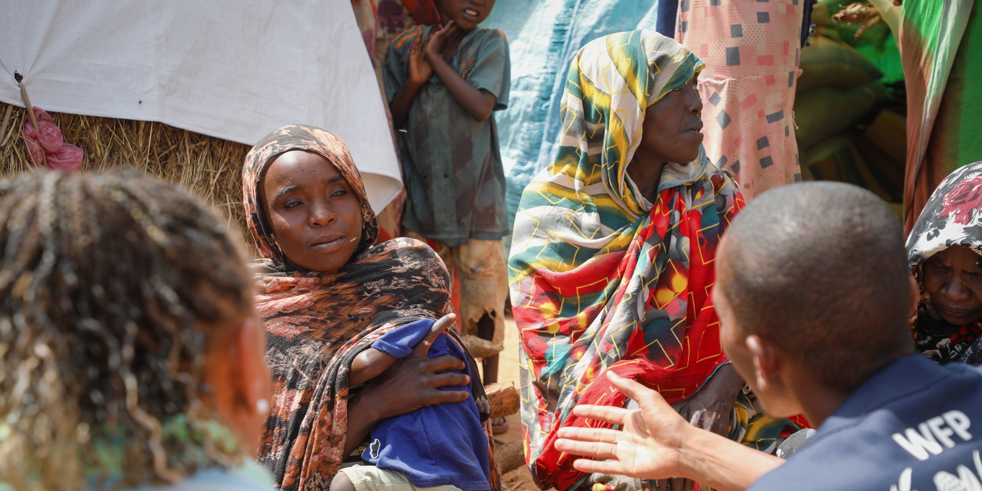 Humanitäres Personal, mit Patricia Danzi, spricht zu Frauen in traditioneller Kleidung im Tschad.