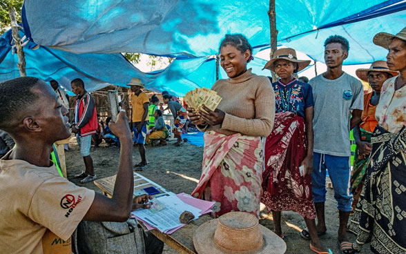 Una mujer en Madagascar recibe asistencia en efectivo para comprar artículos domésticos y alimentos para su familia tras una prolongada sequía.
