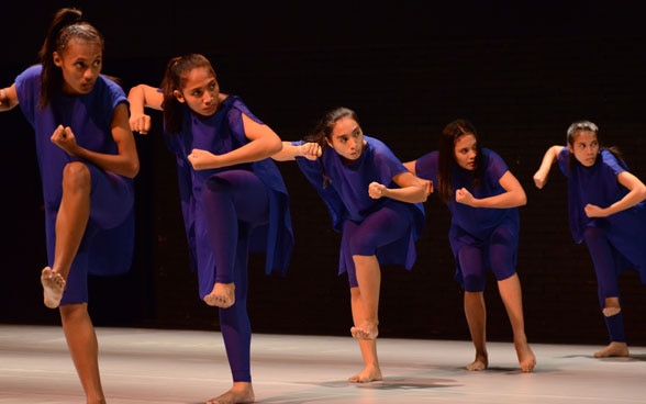 Five Indonesian dancers performing an expressive choreographed piece on stage.
