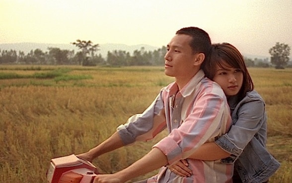 Ein Mann und eine Frau fahren eng umschlungen auf einem Roller.
